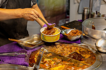 Close-up of Taiwanese braised pork rice in takeaway bowl featuring pork trotter, braised tofu, pickled vegetables, and a soy-marinated egg over white rice