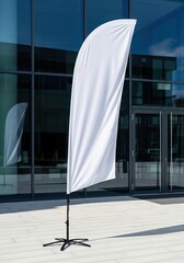 White mockup feather flag standing outside a modern business center for an outdoor event advertisement