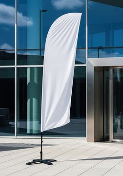 White mockup feather flag standing outside a modern business center for an outdoor event advertisement