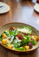 vegetable greens salad with biscuits crispy bacon ground butter and salad dressing in brown plate and white dish on wooden table and top view for vegetables diet healthy food and breakfast eating
