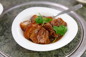 Braised pork knuckle stewed in soy sauce until tender, served in a bowl and garnished with fresh cilantro as a signature Chinese main dish
