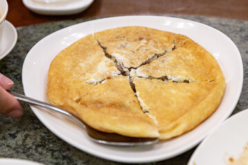 Chinese-style omelet made with preserved radish and beaten eggs, pan-fried to golden brown and sliced into wedges on a white plate