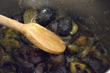 Homemade plum jam boiling in metal pot, close-up preparation of traditional sweet.