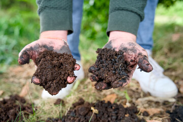 Close-up of two hands cradling a handful of highly fertile, dark soil enriched with organic matter, biochar, and thriving worms.