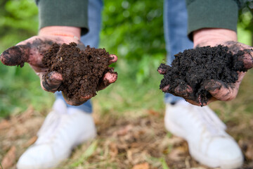 Close-up of two hands cradling a handful of highly fertile, dark soil enriched with organic matter, biochar, and thriving worms.