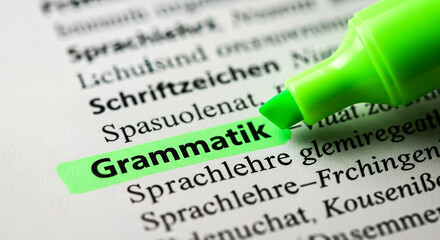 Focus on german grammar learning with a bright green highlighter marking key terms in a dictionary or text.