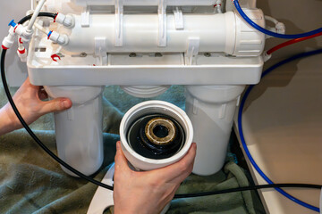 Close up view of dirty used water filter cartridge being removed from the purification system...