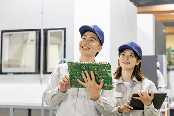 工場でタブレットを使って製品を検査する男女作業員