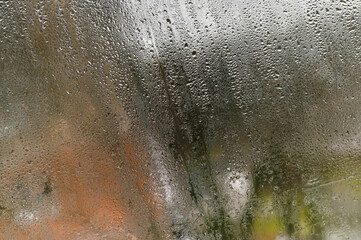 Water trails on glass from temporary organic textures, where light reflections dance along liquid...