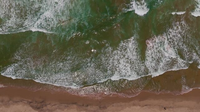 Scenic Coastal Drone View with White Foamy Waves Rolling onto Sandy Beach