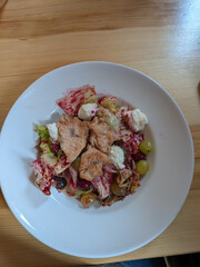 Delicious salad with grilled chicken and fresh ingredients, served on a white plate.