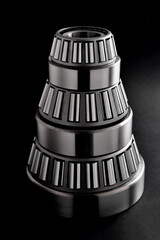 roller bearings stacked in a pyramid on a black background