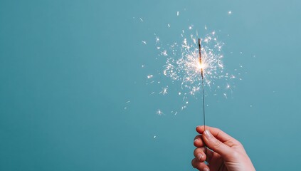 Hand holding a sparkler against a blue background