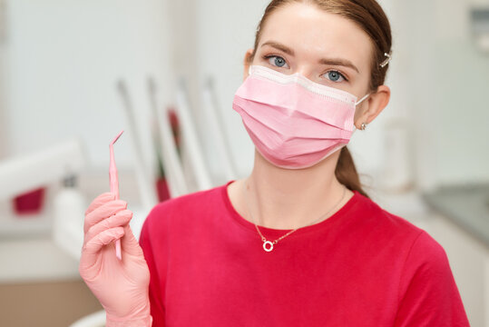 A dentist poses with a dental tool in a clinic, ready for work.