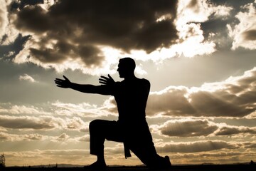 Silhouette of a person practicing martial arts against a dramatic cloudy sky at sunset