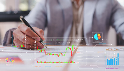 Businessman sitting on desk in office using pen working with Diagrams and graphs on virtual screen. Business strategy, data analysis technology and financial growth concept