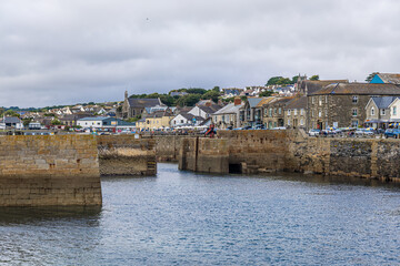 Fototapeta premium Coastal town of Porthleven in Cornwall, UK with harbor, clock tower, beach and houses