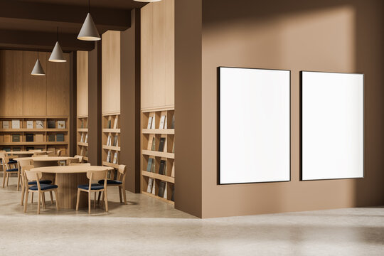 Modern library interior with wooden furniture and two large blank poster mockups on brown wall under soft lighting in minimal design template concept. 3D Rendering