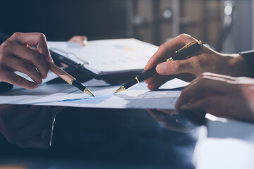 Focused young businessman signing agreement with skilled lawyer in eyeglasses. Concentrated...