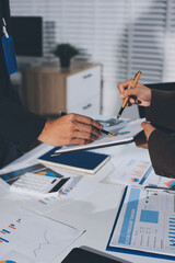 Focused young businessman signing agreement with skilled lawyer in eyeglasses. Concentrated...