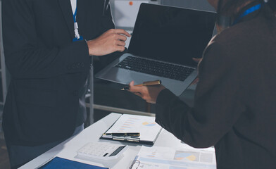 Focused young businessman signing agreement with skilled lawyer in eyeglasses. Concentrated...