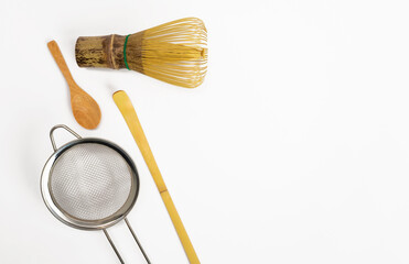 Chasen bamboo for brewing matcha and spoon on a white background.