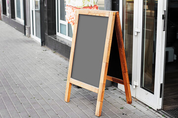 Wooden street chalkboard stand. Blank menu board in front of cafe entrance. Empty outdoor sign...