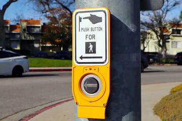 Pedestrian crossing push button on traffic light pole in urban street