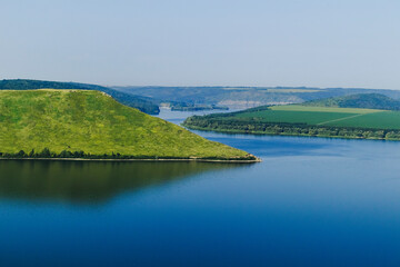 Scenic view of tranquil river with lush green hills and clear blue water, showcasing natural beauty and serene landscape. Bakota bay, Dniester river, Ukraine