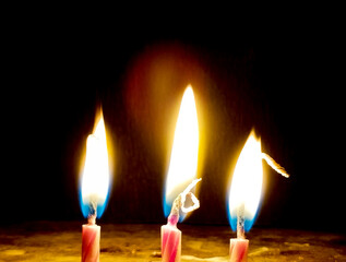 Close-Up of Three Burning Candle Flames in Darkness