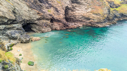 Stunning coastal scenery featuring turquoise water, a cave, and striking rock formations.