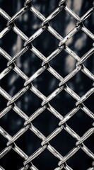 Fototapeta premium Close-up of iron chain-link fence texture and silver metal mesh pattern with sharp focus against dark night sky background showcasing industrial