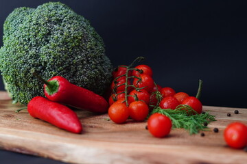 Fresh Broccoli, Cherry Tomatoes, Red Chili Peppers and Herbs on Wooden Board