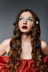 Naklejka premium A young woman in a red dress flaunts festive eye makeup and hairstyle with festive decor 
