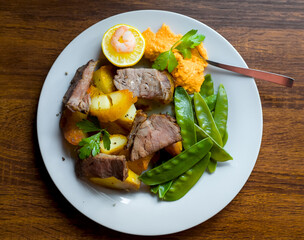 Top View of Sliced Welsh Beef Roast Steak with Sugarsnap Peas, Roasted Potatoes, Pepper Dip, Lemon and Shrimp, British Cuisine
