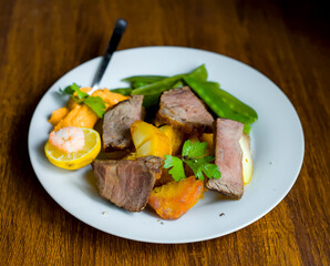 Close-up of Sliced Welsh Beef Roast Steak with Sugarsnap Peas, Roasted Potatoes, Pepper Dip, Lemon and Shrimp, British Cuisine