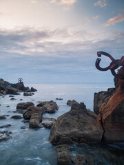 Vertical photo of a seascape with rusty human artifacts