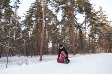 Father and daughter having fun with snow tube in the forest