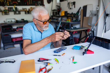 Elderly fisherman watching instructions on a tablet to set up his fishing gear