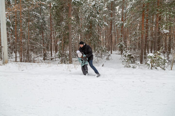 Dad and daughter walking and having fun in snowy winter forest