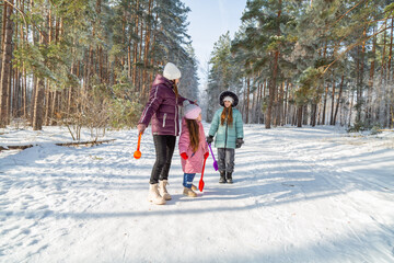 Mother with children walking in nature in the winter forest