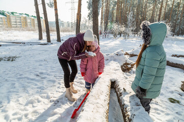 Mother with children playing in nature in the winter forest