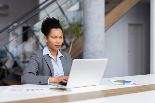 Businesswoman concentrating on her laptop, analyzing data and reports in a bright, modern office environment