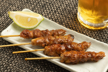 美味しそうにてかっている焼き鳥とビールの注がれたジョッキ