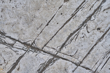 Close-up of a weathered concrete surface with intersecting dark lines and scattered gray specks offering a textured abstract background