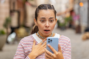 Upset young woman using smartphone typing browsing loses becoming shock sudden lottery results bad...