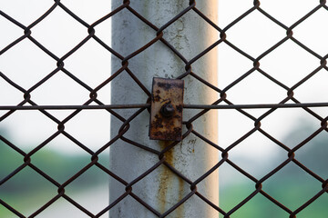 Detail photo of a metal wire fence with a tied rope, creating a rustic and urban textured background.