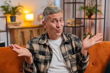 What. Why. Frustrated man with gray hair raising hands in indignant expression asking reason of...