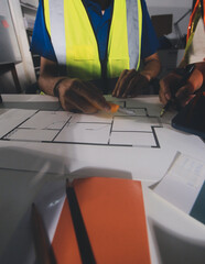Closeup of team of industrial engineers meeting analyze machinery blueprints consult project on...