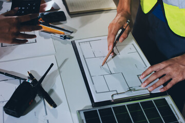 Closeup of team of industrial engineers meeting analyze machinery blueprints consult project on...